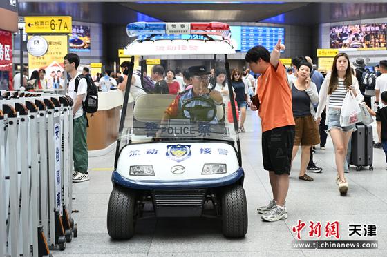 图为北京铁路公安局天津公安处天津站派出所民警在候车大厅巡逻执勤期间帮助旅客解决问题。（北京铁路公安局天津公安处供图）